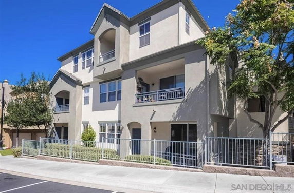 Front view of a multi-story residential building with balconies and gated entrances.