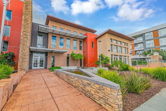 Front view of a modern multi-story building with large windows and a stone pathway.