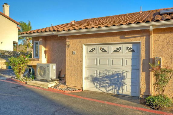 Front view of a house with a garage and terracotta roof tiles.