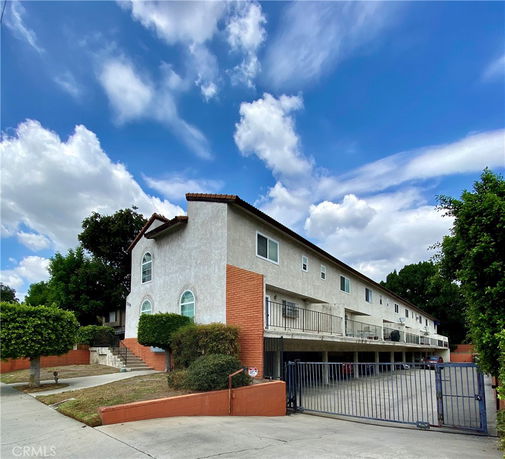 Front view of a multi-story residential building with a gated entrance.
