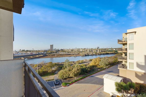 Wide angle view of the surroundings from a building balcony, overlooking a river and distant residential area.