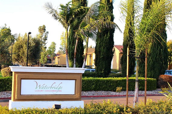 Front view of luxury condominiums with a signboard reading 'Waterbridge Luxury Condominiums'.