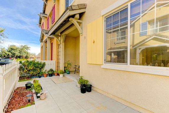 Front view of a two-story house with a yellow facade and a small tiled porch area.