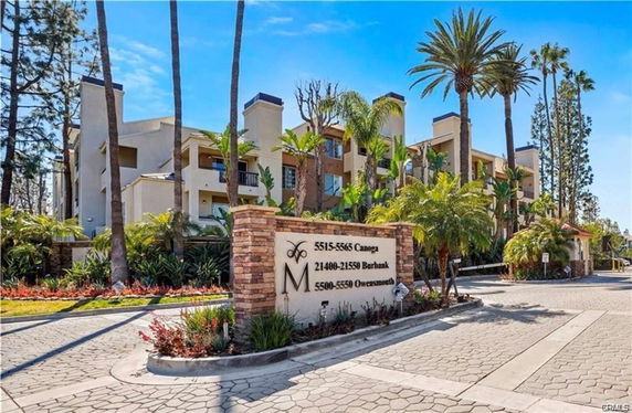 Front view of a multi-story residential building complex with palm trees.