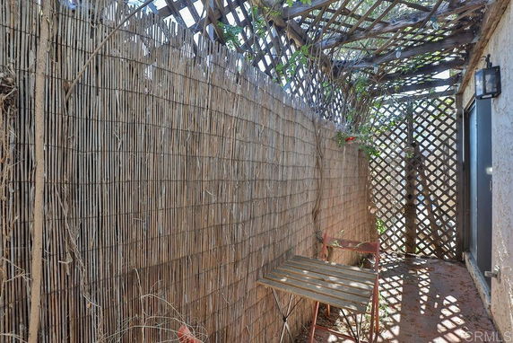 Narrow outdoor space with lattice walls and partial overhead coverage.