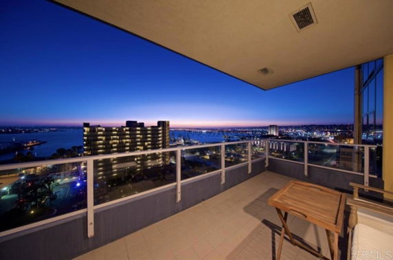 Panoramic view from a balcony overlooking a cityscape and water at dusk.