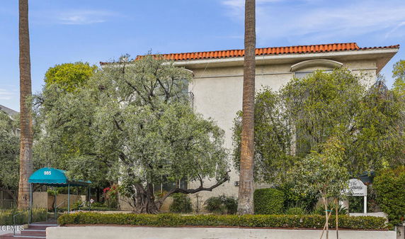 Front view of a two-story building with a red-tiled roof and surrounded by trees.