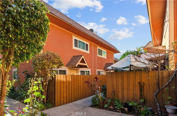 Front view of a two-story house with a wooden fence and small garden.
