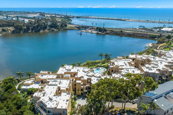 Aerial view of a residential complex near a large body of water with a distant ocean backdrop.