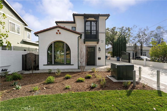 Front view of a two-story house with arched window and balcony.