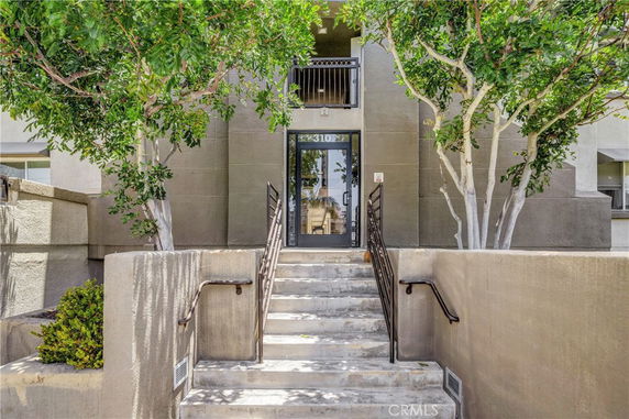 Front view of a building entrance with stairs and handrails.