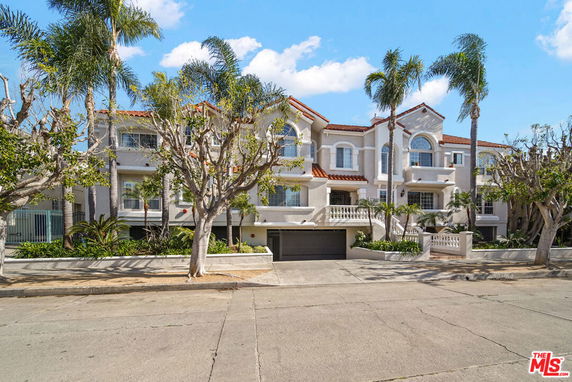 Front view of a multi-story house with an arched window design and red-tiled roof.
