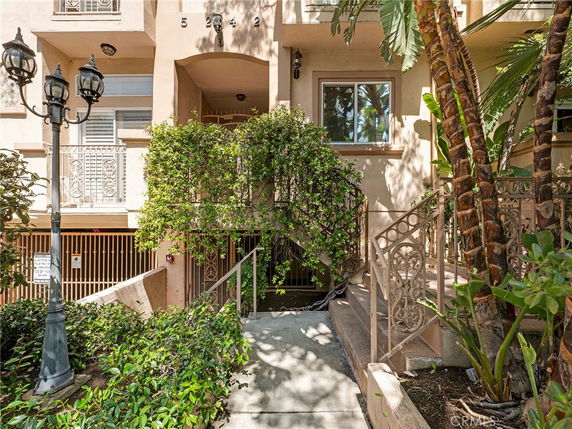 Front view of a multi-story building with decorative fencing and lush greenery.