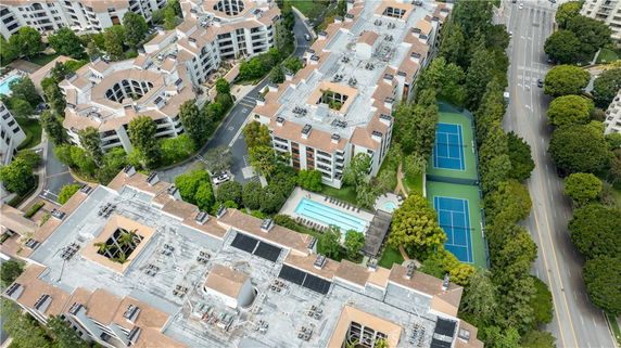 Panoramic aerial view of a residential complex with tennis courts and a swimming pool.
