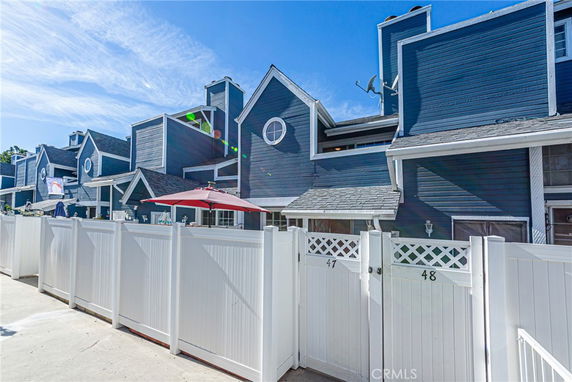 Front view of a multi-story townhouse with a white fence and a red umbrella.