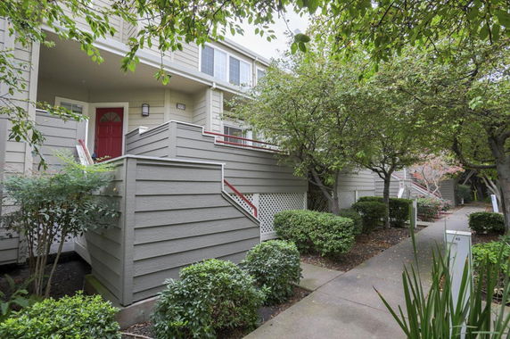 Front view of a multi-story house with a red door and covered entrance.