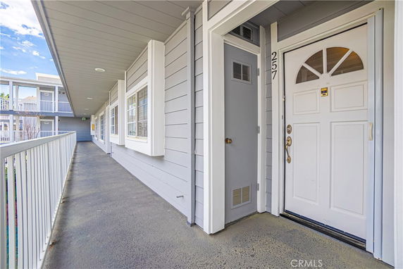 Exterior view of the entrance to an apartment with a white door and a grey facade.