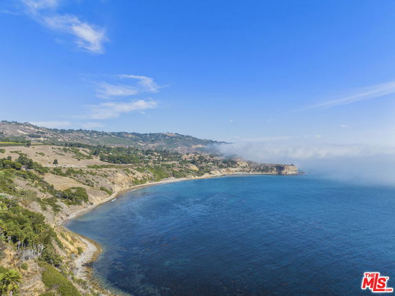 Aerial view of a coastal landscape with blue ocean and rugged cliffs.