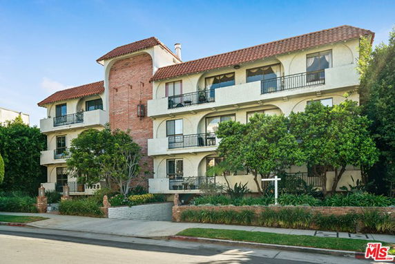 Front view of a multi-story building with balconies and a red-tiled roof.
