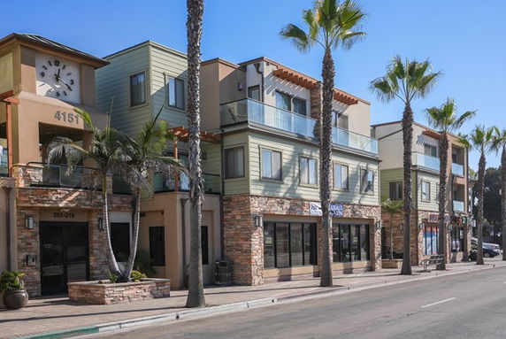 Front view of a multi-story building with retail spaces at the ground level.