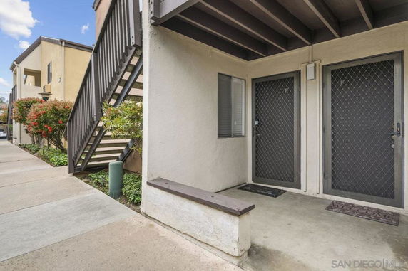 Front view of an apartment building with external stairs and multiple entry doors.