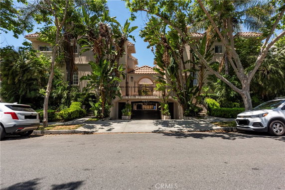 Front view of a multi-story house with trees and plants.