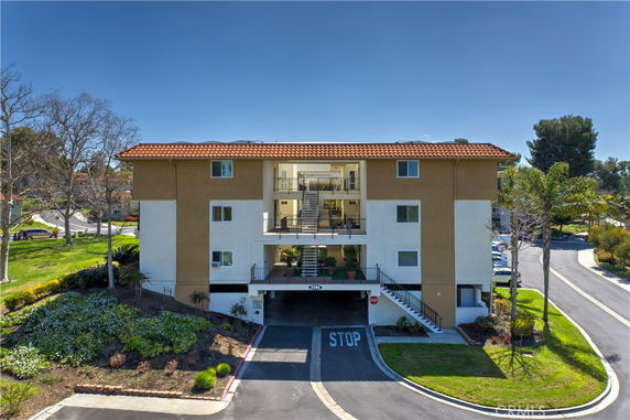 Front view of a multi-story building with a central open corridor and a tiled roof.