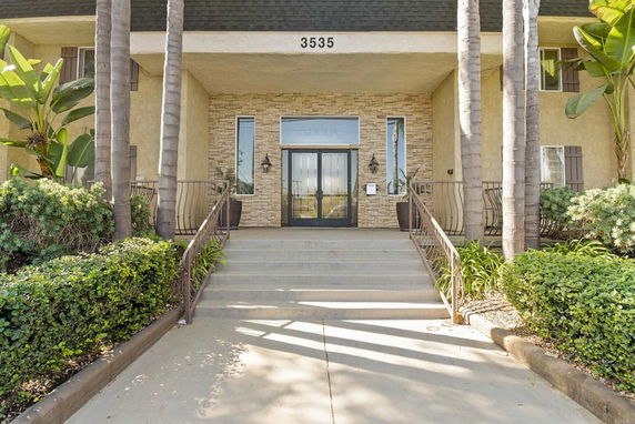 Front view of a building entrance with stone accents and steps leading to a door.