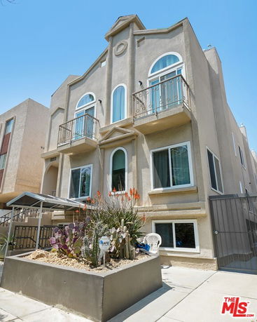 Front view of a multi-story building with balconies and arched windows.