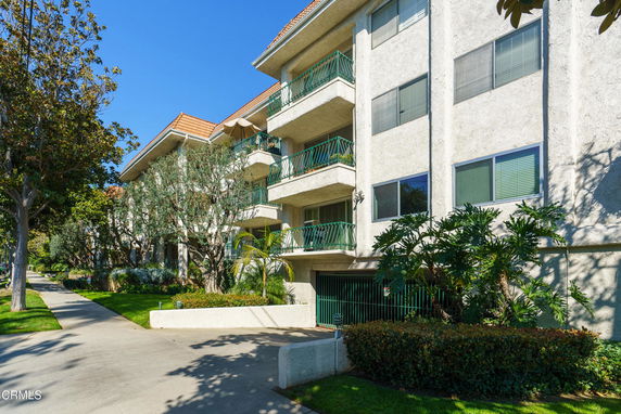 Front view of a multi-story building with balconies and green railings.