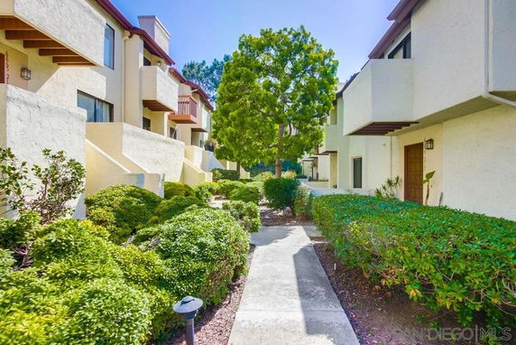 Front view of a multi-story residential building with balconies and a pathway.