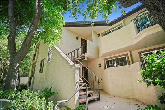 Front view of a two-story building with balconies and stairs leading to the entrance.
