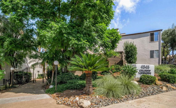 Front view of a townhouse with gated entrance and surrounding greenery.
