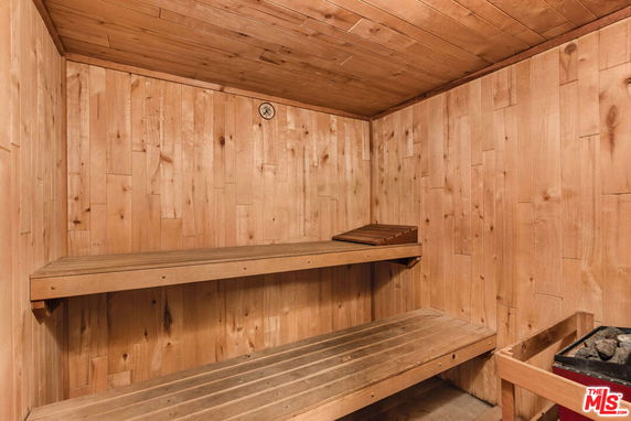 Interior view of a wooden sauna with seating and a heat source.