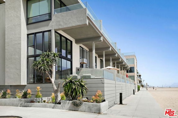 Front view of a multi-story beachfront building with large windows and balconies.