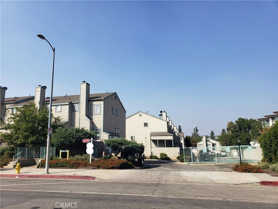Front view of a multi-story building with multiple chimneys and a gated entrance.
