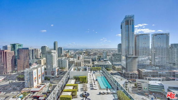 Panoramic view of a cityscape from a high vantage point with tall buildings and a rooftop swimming pool.