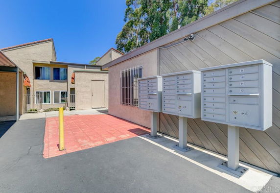 Front view of a multi-story building with mailboxes in front.