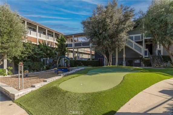 View of a building with an adjacent outdoor play area featuring a small golf putting green.