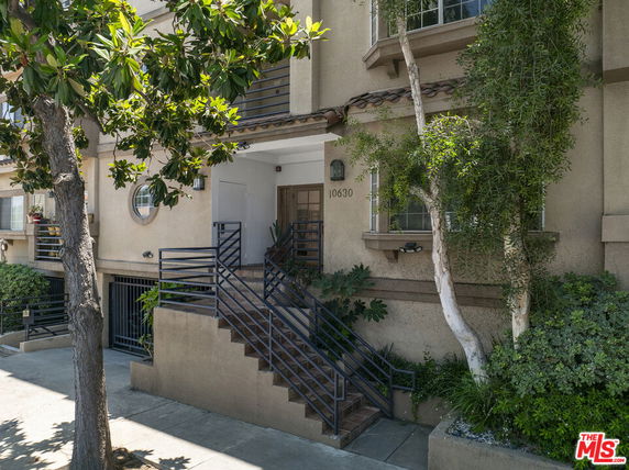 Front view of a multi-story building with a gated entrance and staircase.