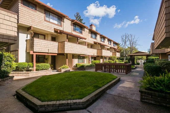 Front view of a multi-story residential building with balconies and a landscaped courtyard.
