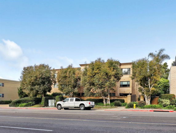 Front view of a three-story building with trees in front.