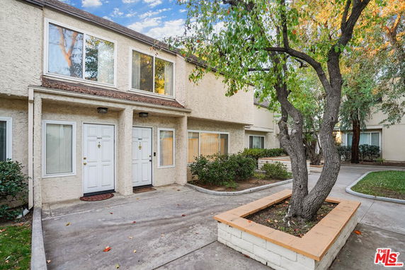 Front view of a townhouse with two entry doors and large windows.