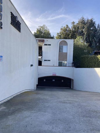 Outdoor view of a building with a driveway leading to a covered parking area.
