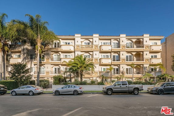 Front view of a multi-story apartment building with balconies and a symmetrical facade.