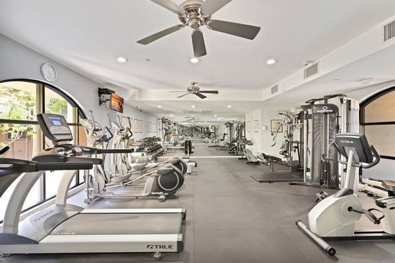 Indoor gym area with various exercise equipment and mirrors on the walls.
