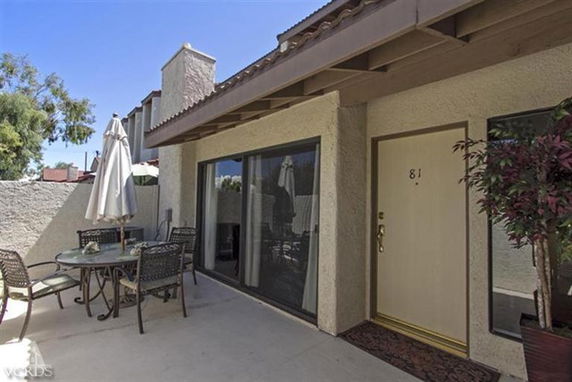 Front view of a house with a small patio and outdoor seating area.