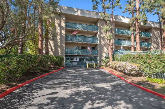 Front view of a multi-story building with balconies and an entrance driveway.
