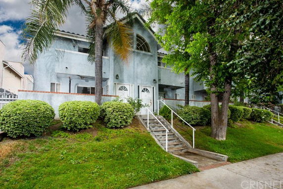 Front view of a two-story residential building with a staircase leading to the entrance.