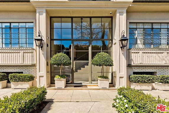 Front view of a building with large glass doors and potted plants.